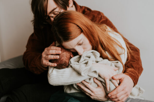 mama i tata przytulający córkę po porodzie na sesji fotograficznej w Poznaniu